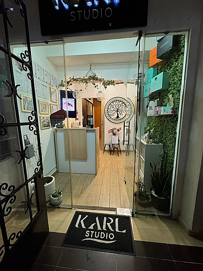 Fachada de KARL Studio de noche: letrero negro con letras blancas, puerta de vidrio y muro verde